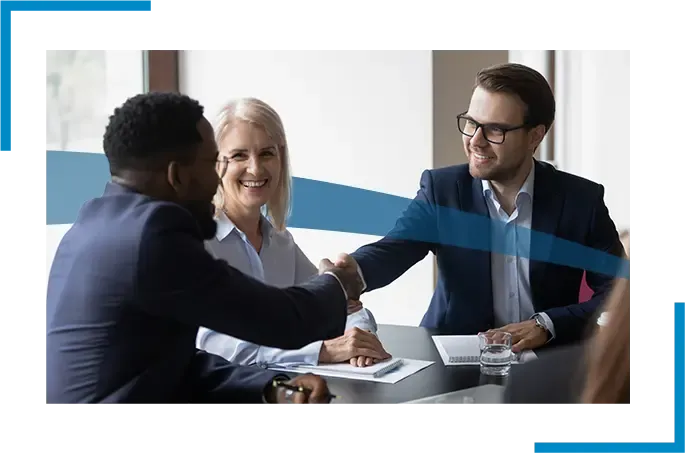 Three people at a meeting with two of them shaking hands.